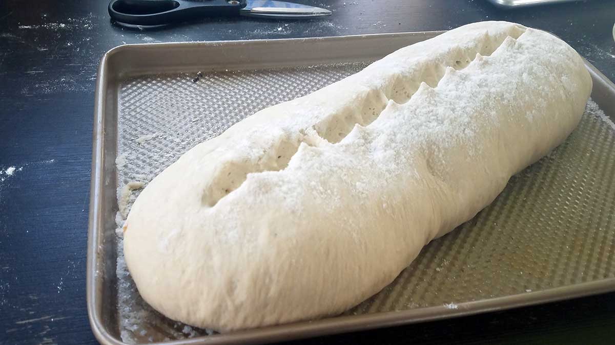 Scoring the Cuban bread loaf before baking.