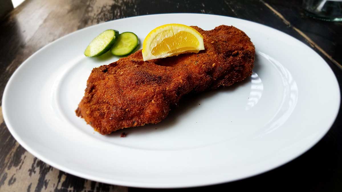 Schweine-Schnitzel made with pork cutlet served with lemons and cucumber.